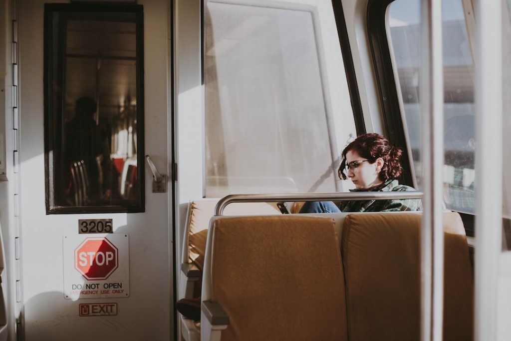 a woman sits in the back of a train car, leaning against the window