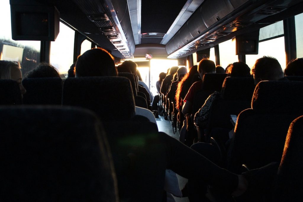 the view from the back of a tour bus filled with people driving into bright sunshine