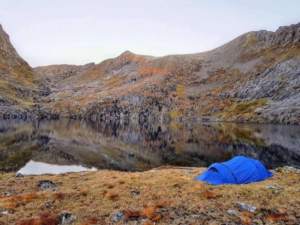 A blue tent beside the fields and a water body in Norway