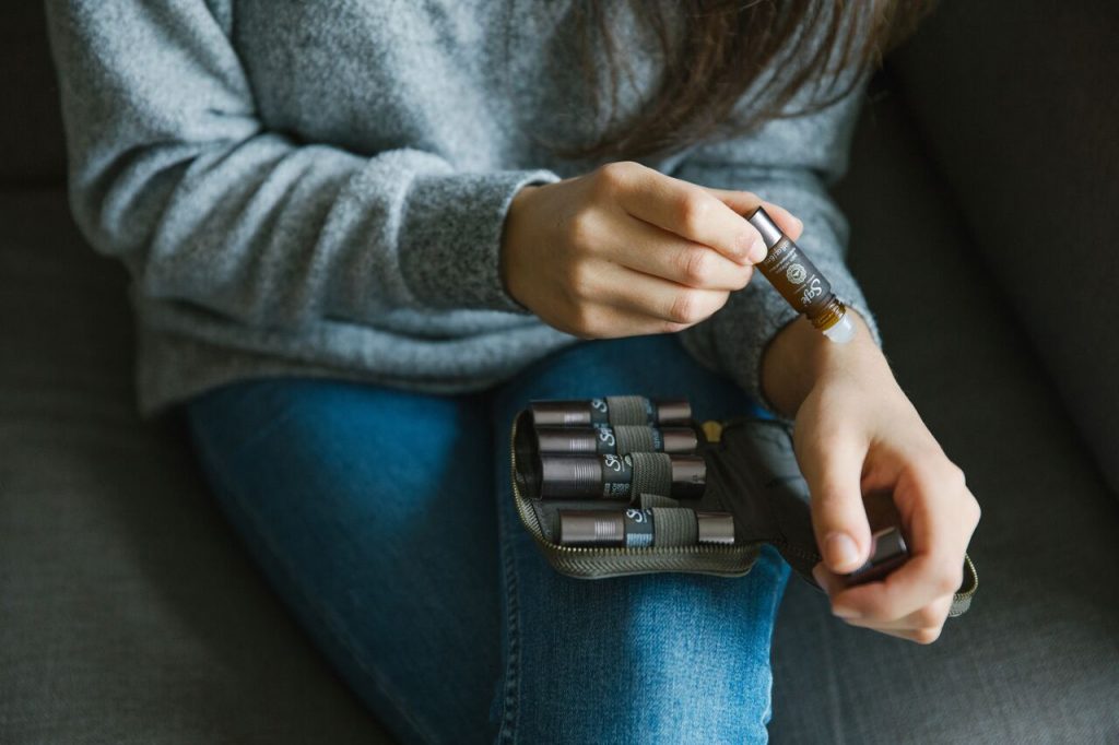 Traveller applies aromatherapy rollerball oils to her pulse points for wellness
