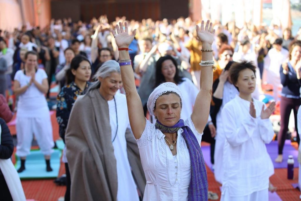 A woman attending the International Yoga Festival celebrates with her arms in the air