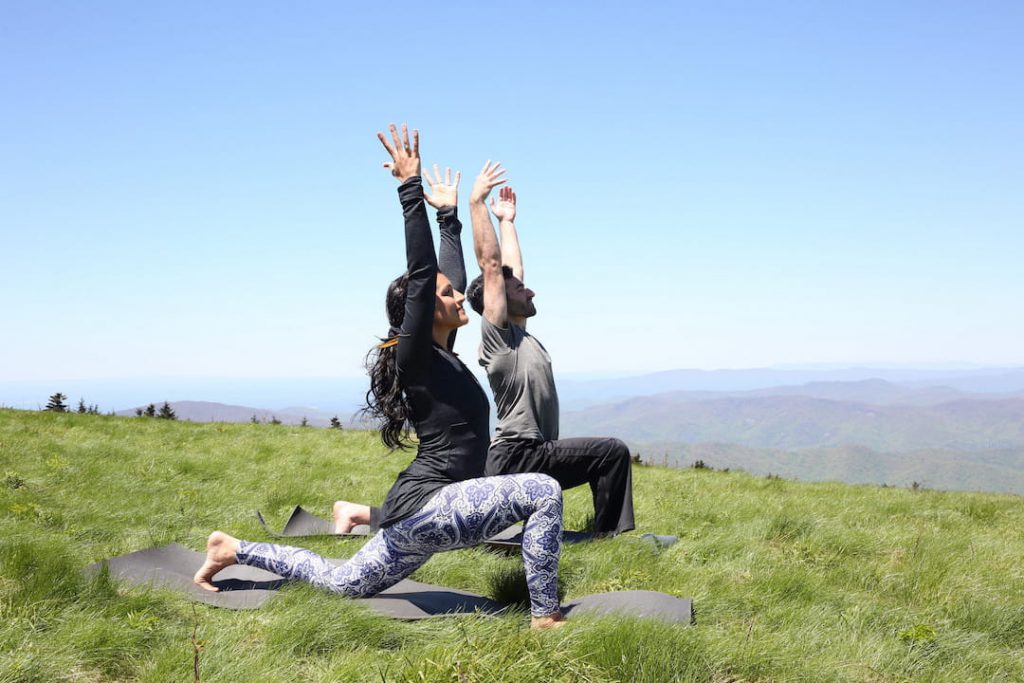 a man and woman practice a yoga pose outdoors