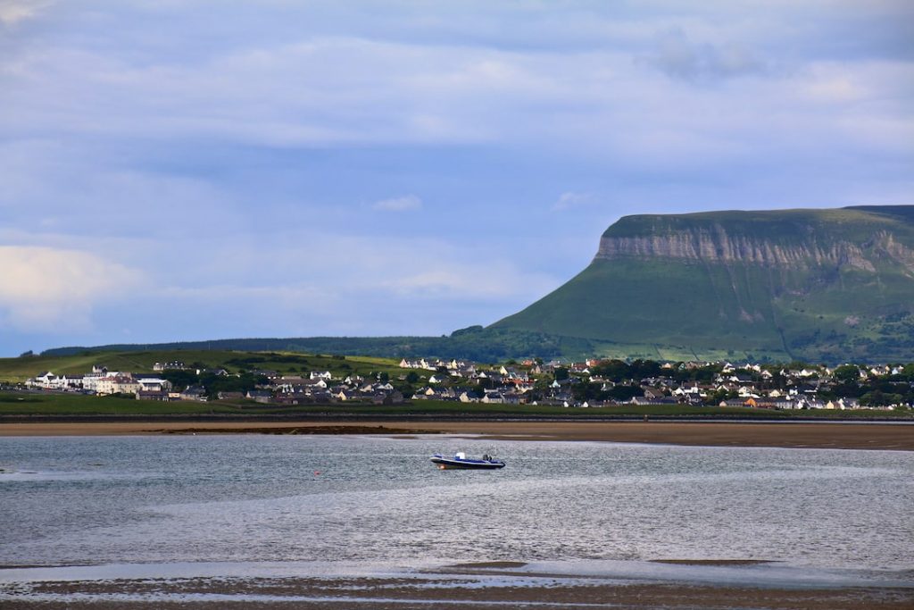 Queen Maeve's hill with a view of a boat on the ocean and a surrounding town