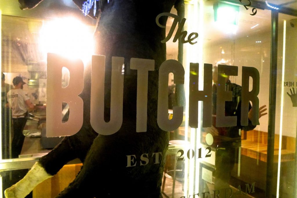 A close-up of a store window that reads "The Butcher, est 2012"