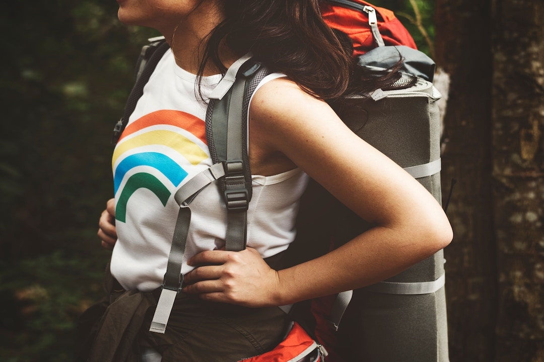 close-up of a woman wearing a shirt with a rainbow on it carrying a backpack