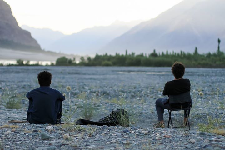 two people sit back and relax looking out at a valley in northern Pakistan