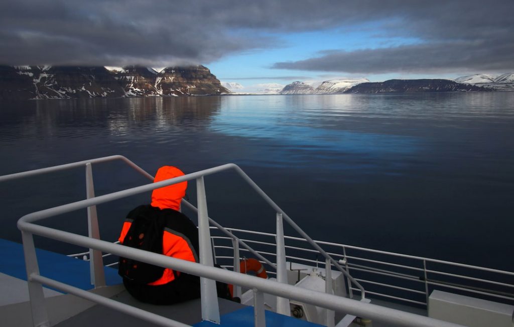 Person sitting on a ship looking out into the icebergs