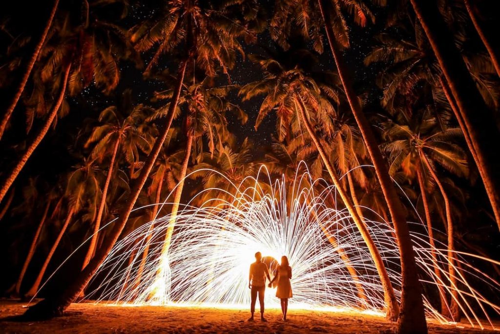 A couple hold hands in front of a burst of light