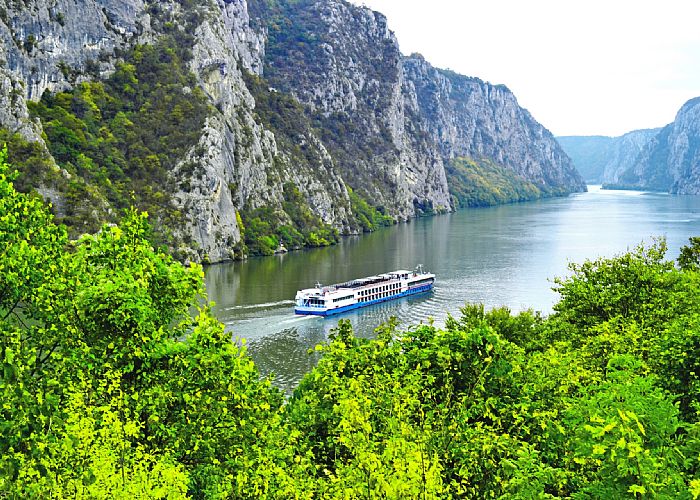 A river cruise ship sails through a valley