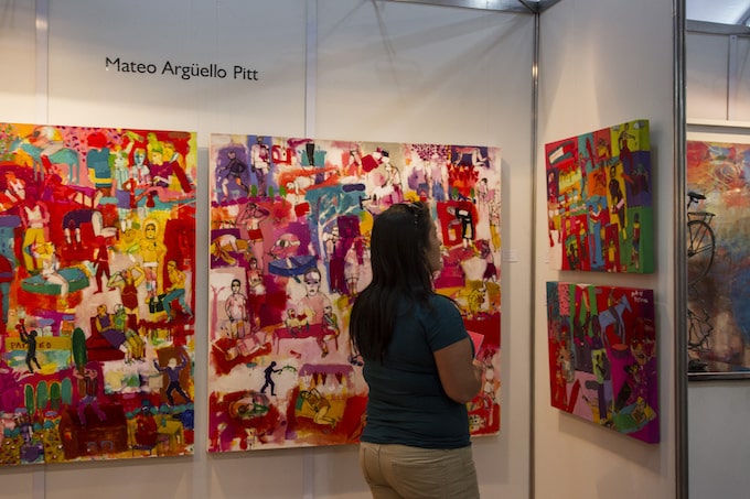 A woman stands and looks at art in Havana
