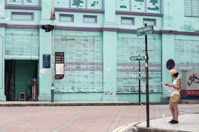 A woman stands reading a map on a street corner in George Town, Malaysia