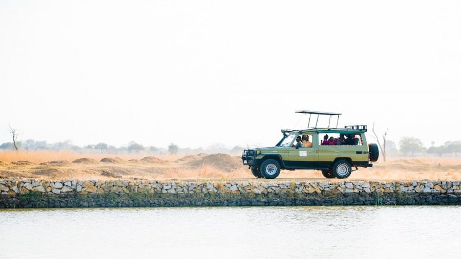A safari truck travelling alongside a body of water in Africa