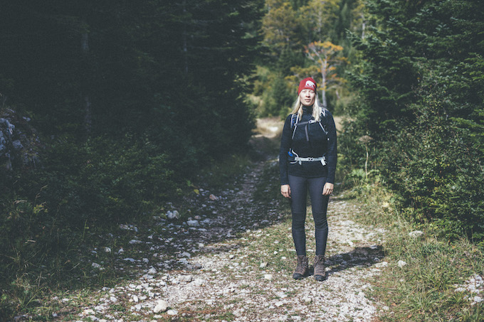 a woman on a trail in hiking gear surrounded by trees