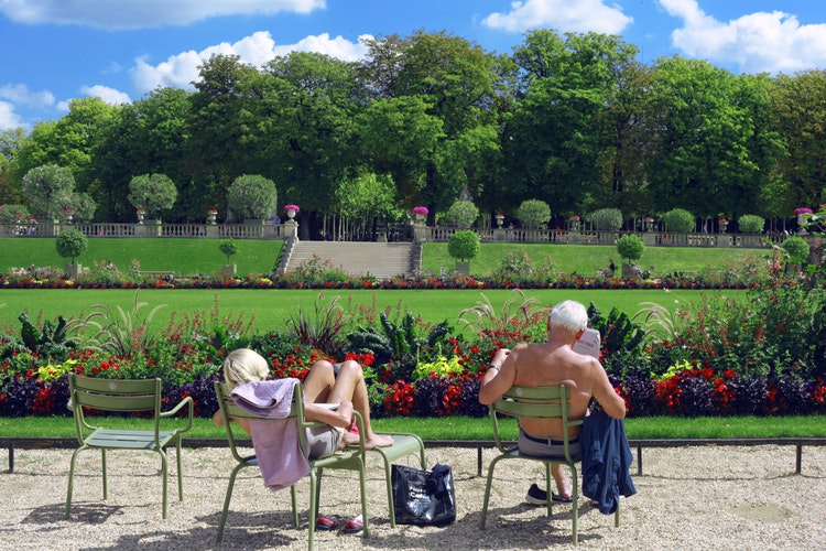 man sitting on green chair reading book, and a woman sunbathing