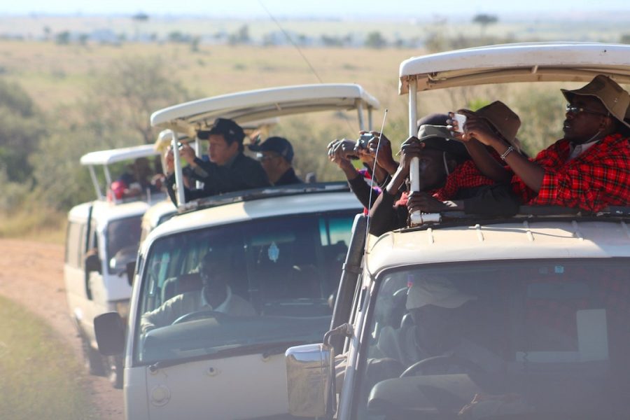 People reaching out of a safari truck to capture a photo in Kenya