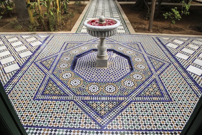 Traditional yard in a riad in Morocco with mosaic tiles floor and a fountain with petals