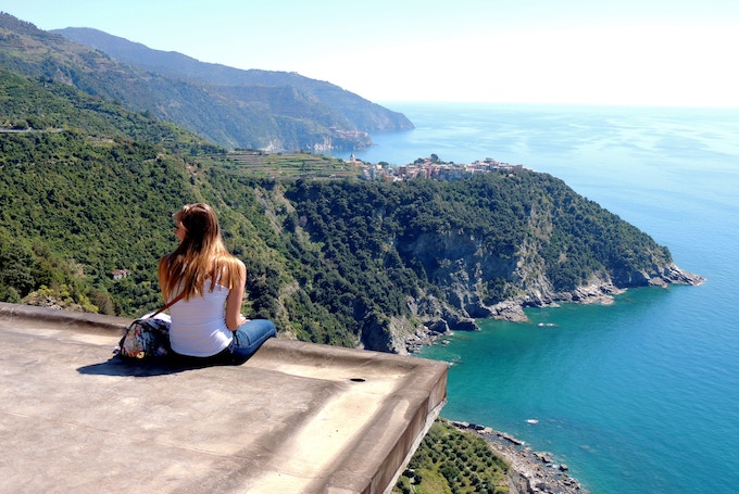 A woman sitting on a ledge in Cinque Terre, Italy