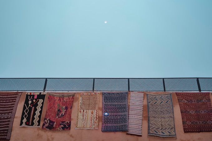 Moroccan rugs hung over a fence on a sunny day in Marrakesh
