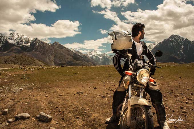 a shot of man on his motorbike looking back at the mountains of pakistan
