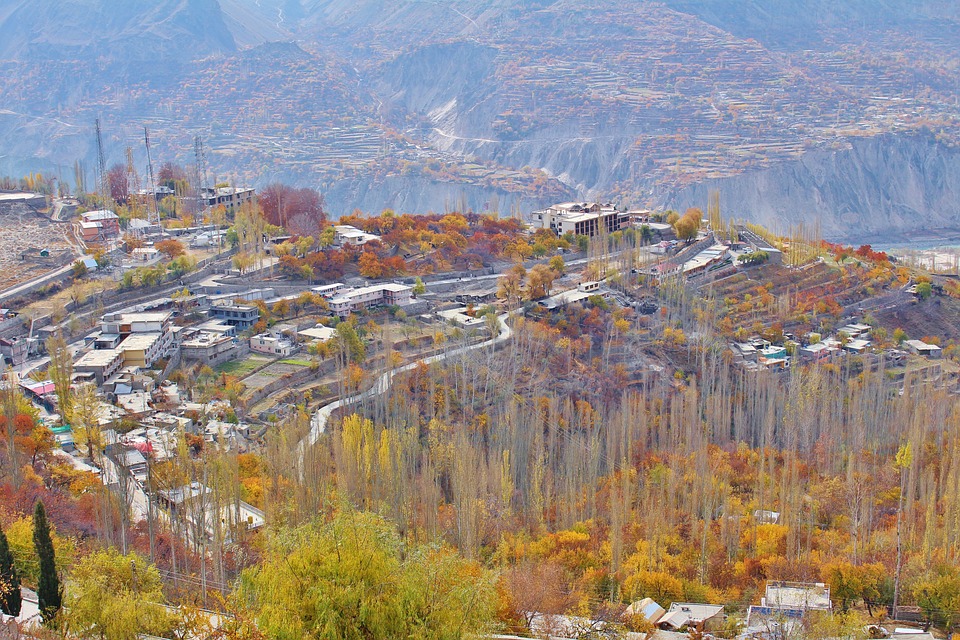 a developed village in a valley of green orange and yellow - hunza