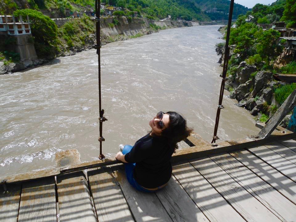 a woman sits on a bridge over the river