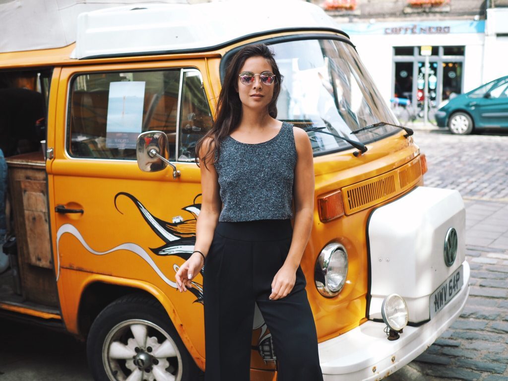 a woman with sunglasses stands in front of a yellow van with graffiti on it