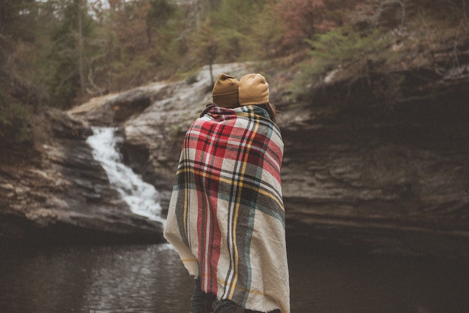 Two women sharing a blanket by a river