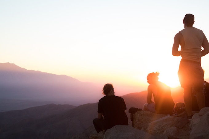 Three people on a cliff in Joshua Tree, California