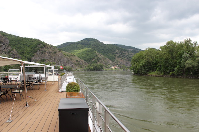 A river cruise ship floating through a green, hilly area