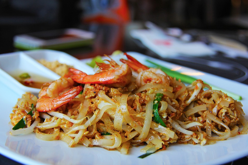 a plate of rice noodles topped with pink shrimp and vegetables