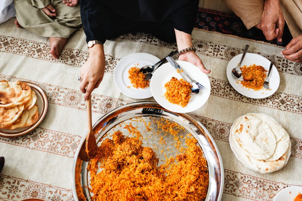 a big plate of rice being served to a number of people