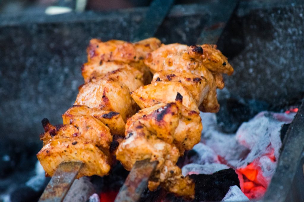 marinated chicken being cooked over hot coals