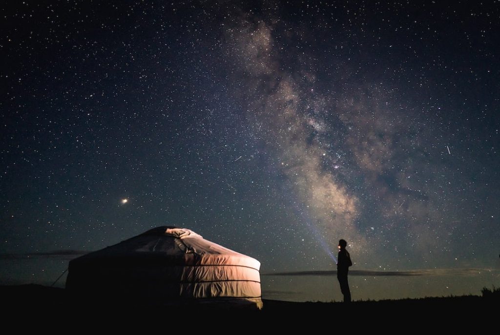 Person standing beside a ger at night in the Gobi Desert, Mongolia