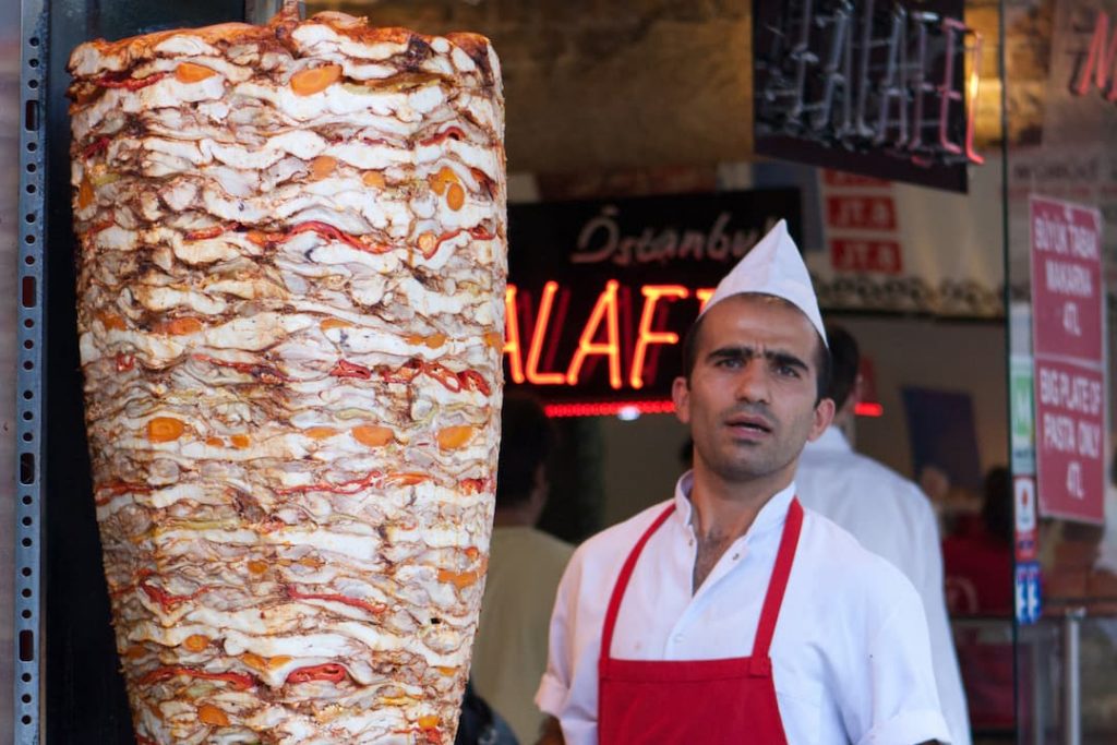Doner kebab vendor standing beside spit of meat in Istanbul, Turkey