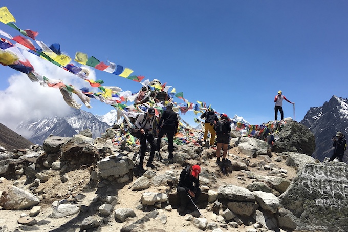 a group of people standing at a view point in the himalayas with colourful flags