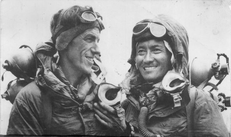 black and white picture of two smiling climbers in their summit gear
