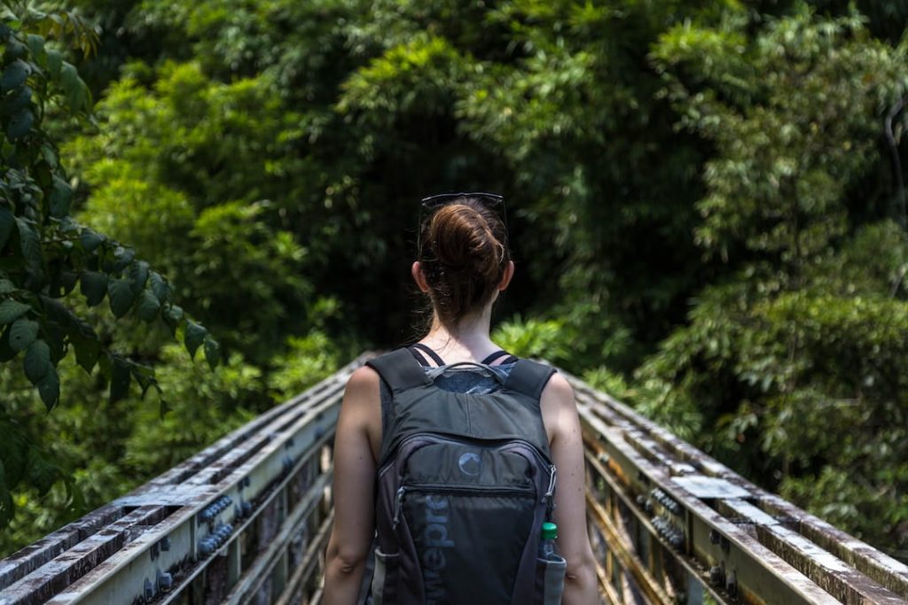 Woman walking across a bridge wearing a backpack