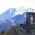 a group of trekkers walking up to a stone doorway structure in the mountains