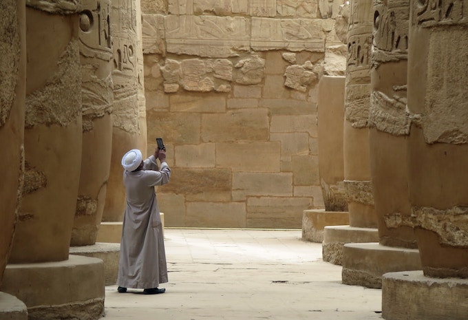 A man taking a photo of a temple in Luxor, Egypt