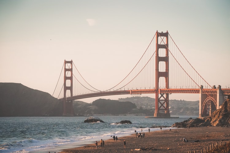 people walking near red bridge on body of water during daytime