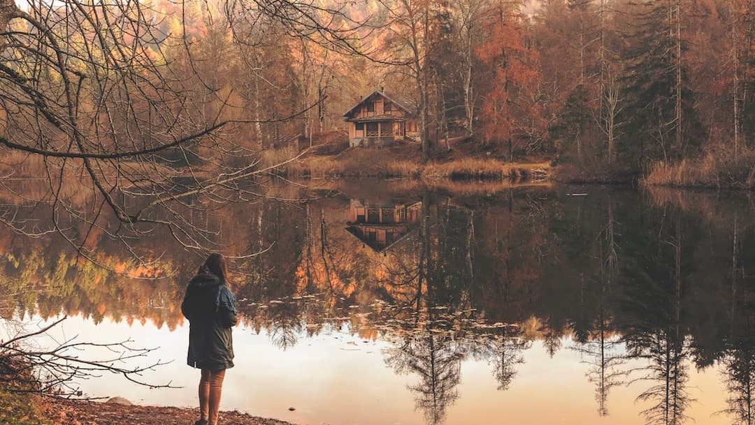 A woman standing in front of a lake in the Falll