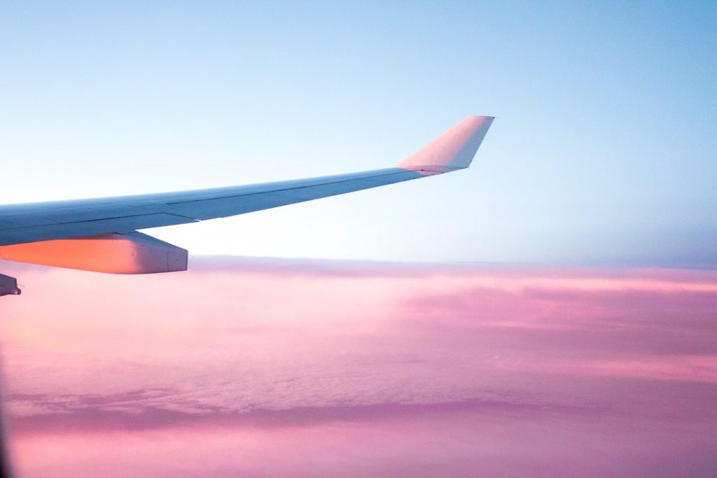 View of an airplane wing from the window with a pink sky in the background