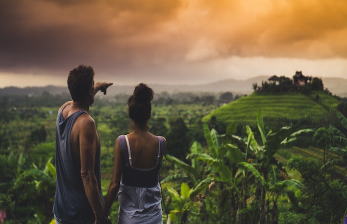 A couple holding hands and pointing out onto a jungle in Bali