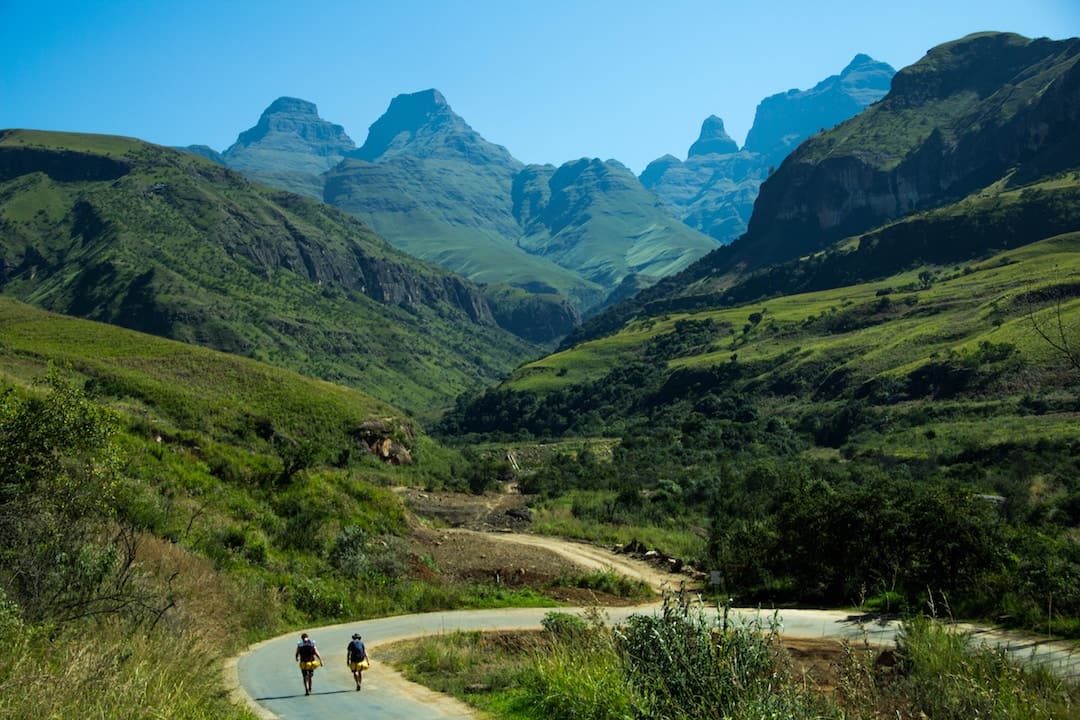 Two people walking on a path amongst green hills
