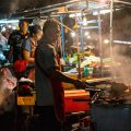 A man roasting chicken at a market in Laos
