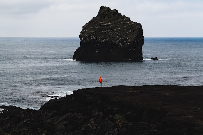 a person standing on a black sand beach in Iceland