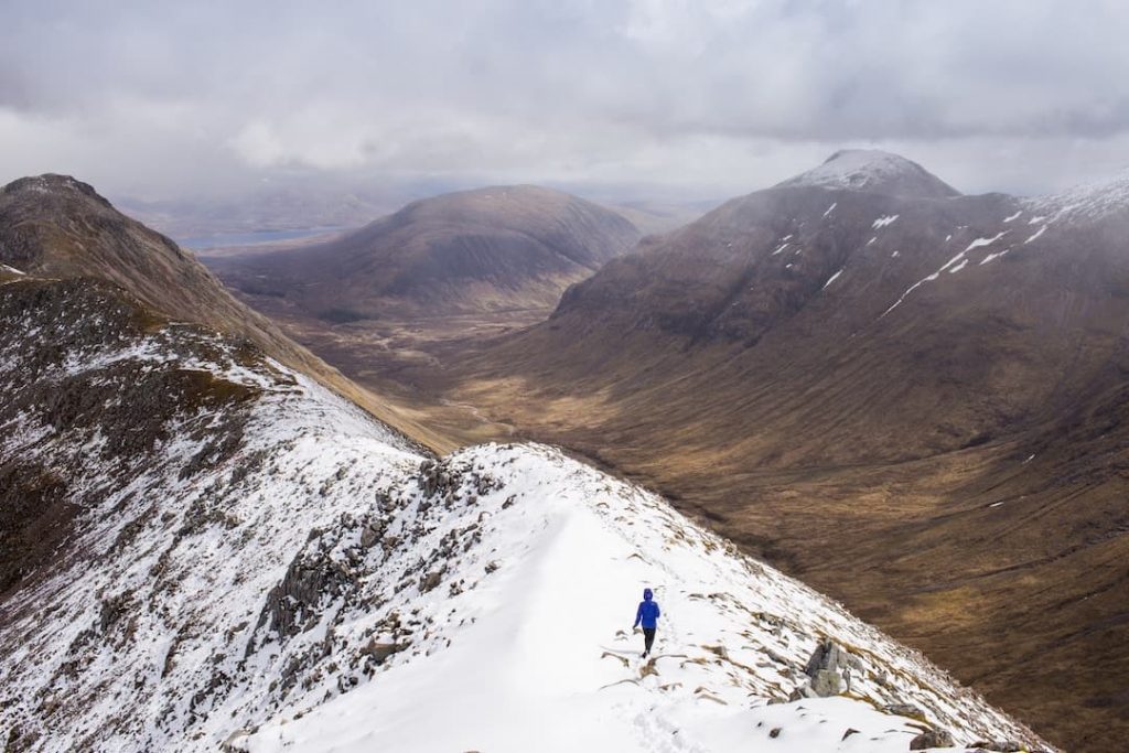 Person walking across a mountain in Glencoe, Scotland