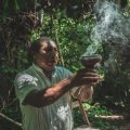 man holding brown pot with smoke