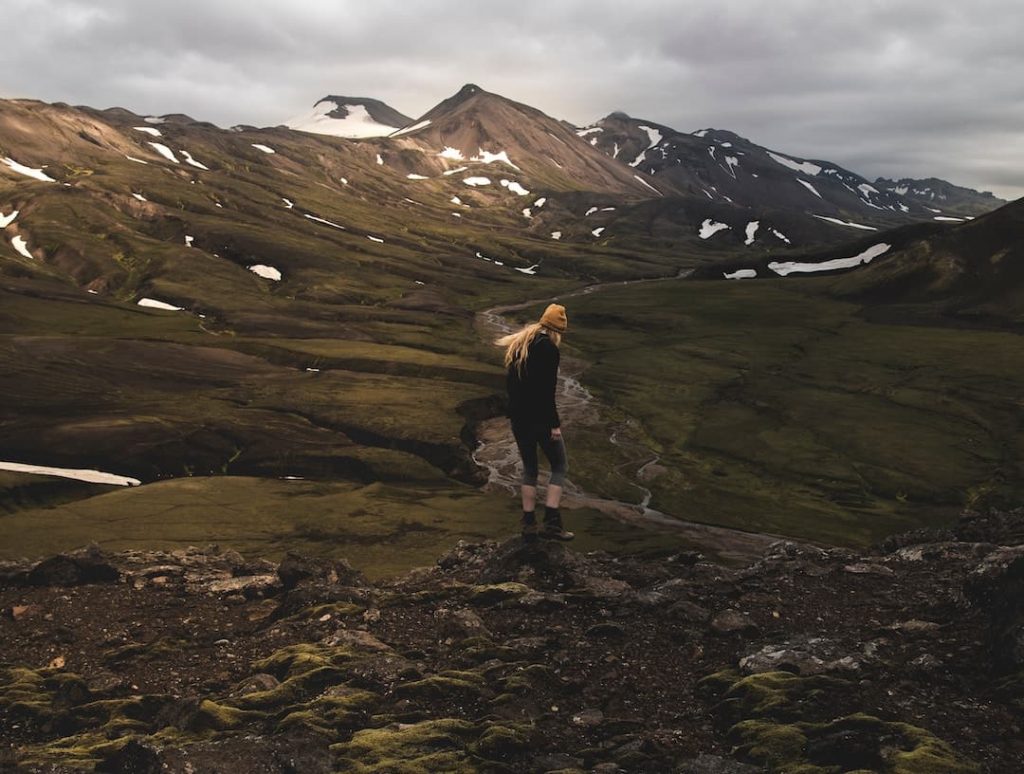 Woman standing at a lookout point with mountains in the background in Iceland