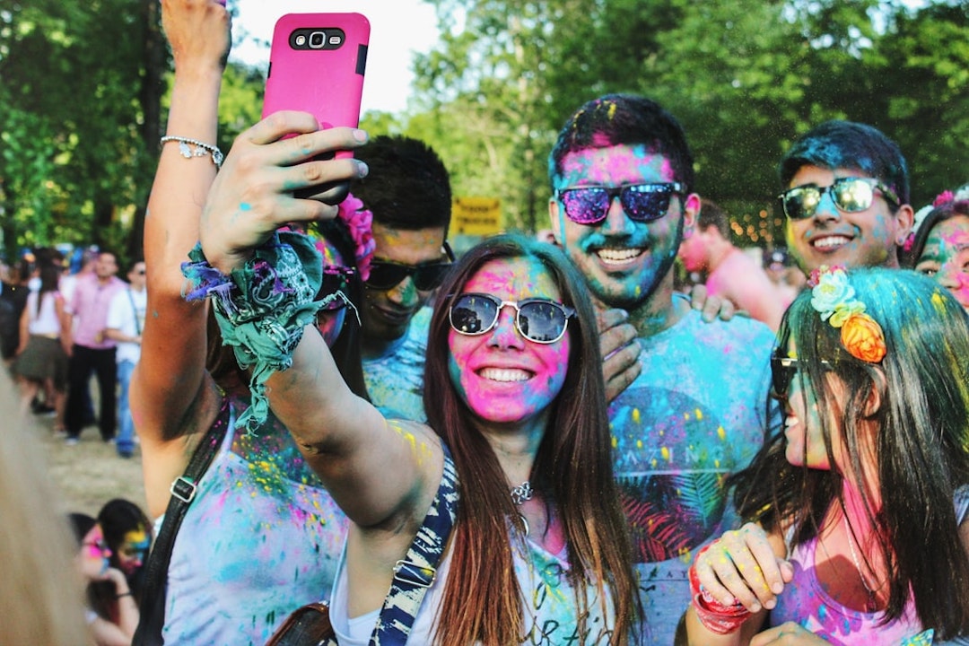a group of people with colour on their faces taking a picture of themselves